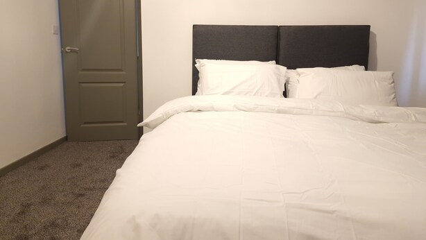 Un dormitorio con cama, puerta y cabecero.