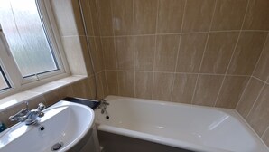 Un baño con una bañera blanca, un lavabo y un ventanal.