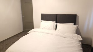 Una habitación de hotel con cama, puerta y cabecero.