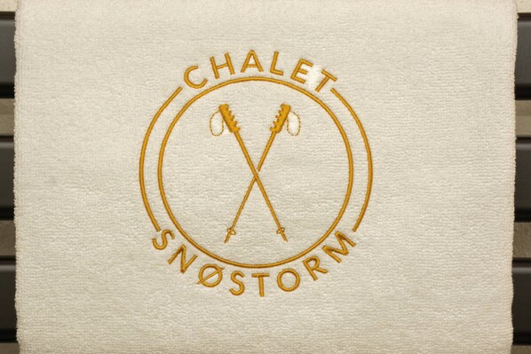 A towel with a circular emblem featuring crossed ski poles and the text "CHALET SNÖSTORM".