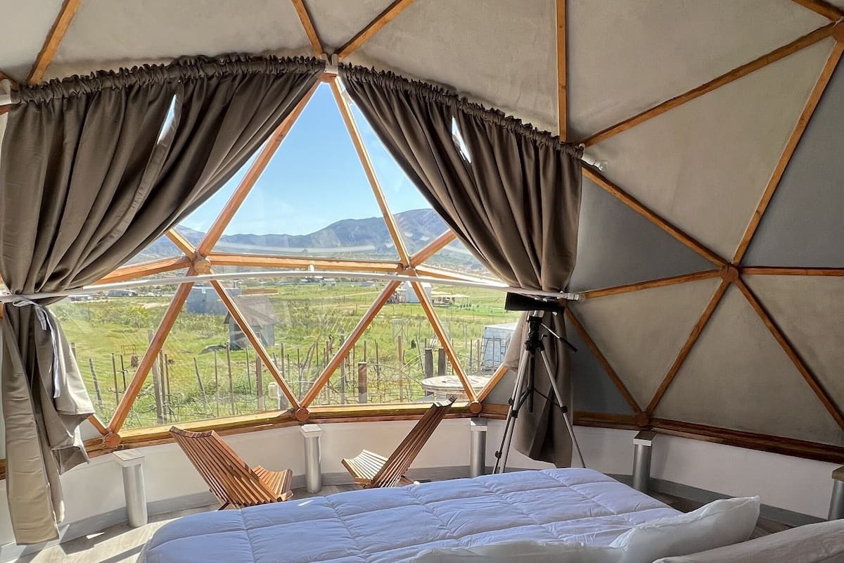 Een kamer met een bed, gordijnen en uitzicht op een landschap.