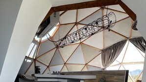 A modern loft-style room with a sloped ceiling, a built-in kitchen, and a patterned floor. - Santerra, Guadalupe Valley (Valle de Guadalupe)