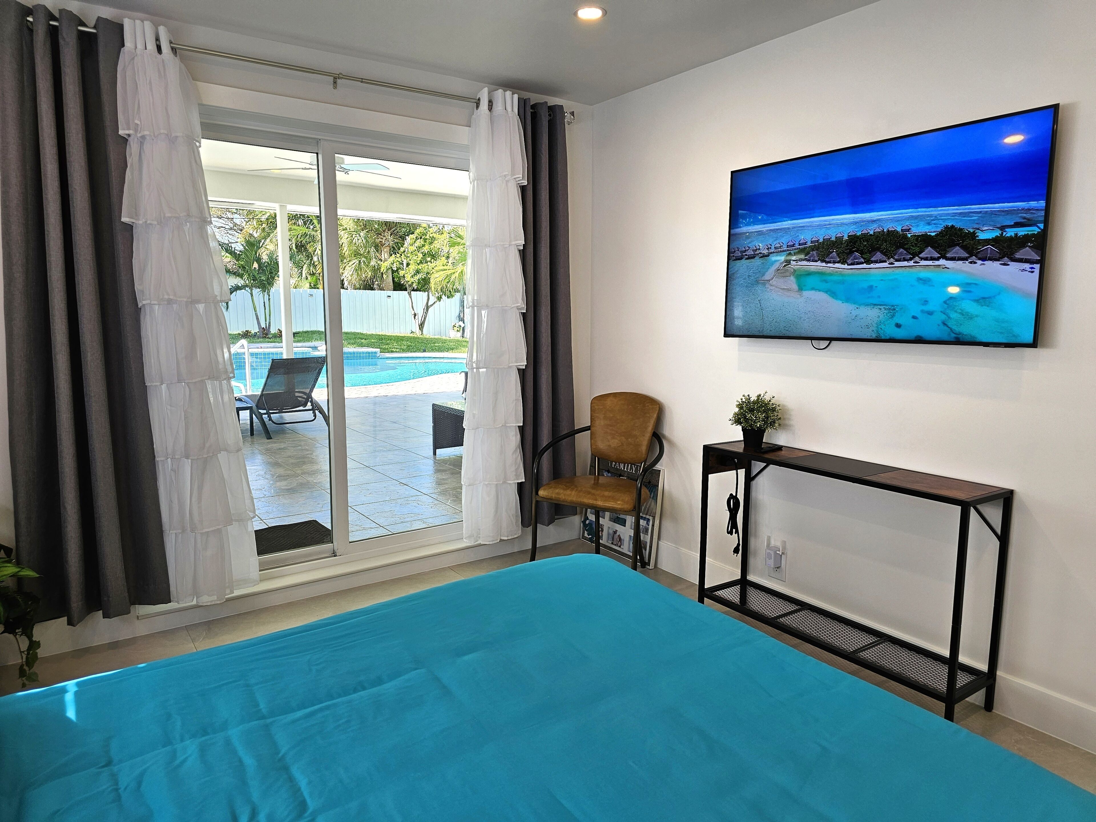 Una stanza con un letto grande, una sedia, un tavolino e una TV che mostra una spiaggia.