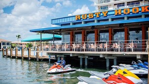 A waterfront restaurant named Rusty Hook with outdoor seating and jet skis docked nearby.