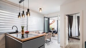 A modern kitchen with a central island, a dining area with chairs, and a view of the outside. - Beach Villa Valentina Apartment III (Okrug Gornji)