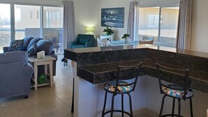 Una cocina moderna con una isla curva, dos taburetes de bar y un ventilador de techo.