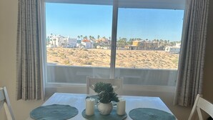 Una mesa de comedor con vista a una playa y edificios al fondo.
