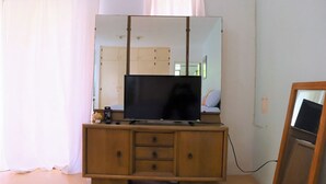 A room with a wooden cabinet, a television, and a large mirror.