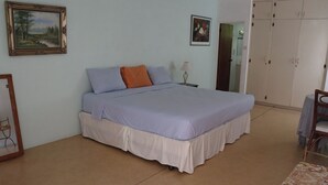 A bedroom with a bed, a nightstand, a lamp, a wardrobe, and a framed picture on the wall.