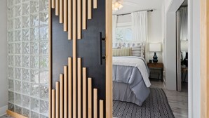 Une chambre à coucher comprenant un lit, une table de chevet, une lampe et donnant sur une salle de bain avec douche et toilettes.