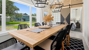 Un espace repas avec une table en bois, des chaises noires et un lustre moderne.