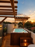 Terraza en la azotea con jacuzzi, cubierta de madera, pérgola y vistas a la puesta de sol.