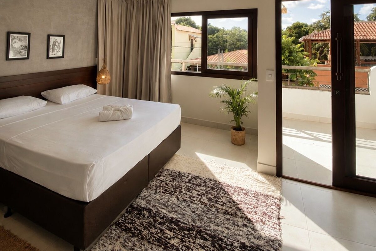 A bedroom with a large bed, a ceiling fan, a window with a view, and a sliding glass door leading to an outdoor area.