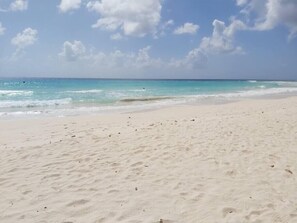 Ein sandiger Strand mit sanften Wellen und blauem Himmel.