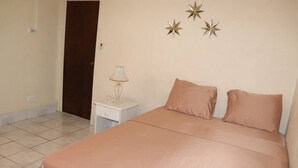 A bedroom with a bed, a nightstand, and a lamp. - Ocean View Apartment B with AC (Bridgetown)