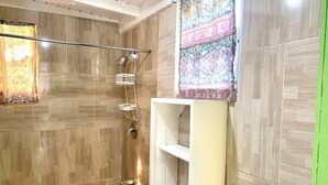 A modern bathroom with a shower, a toilet, and a sink with a mirror. - Dover Beach Tiny House w kitchen (Oistins)