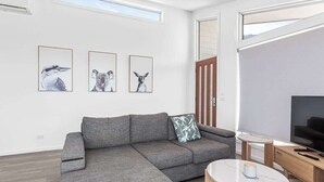A modern living room with a grey sectional sofa, a small round table, and three framed animal prints on the wall. - Apollo Bay Getaway (Apollo Bay)