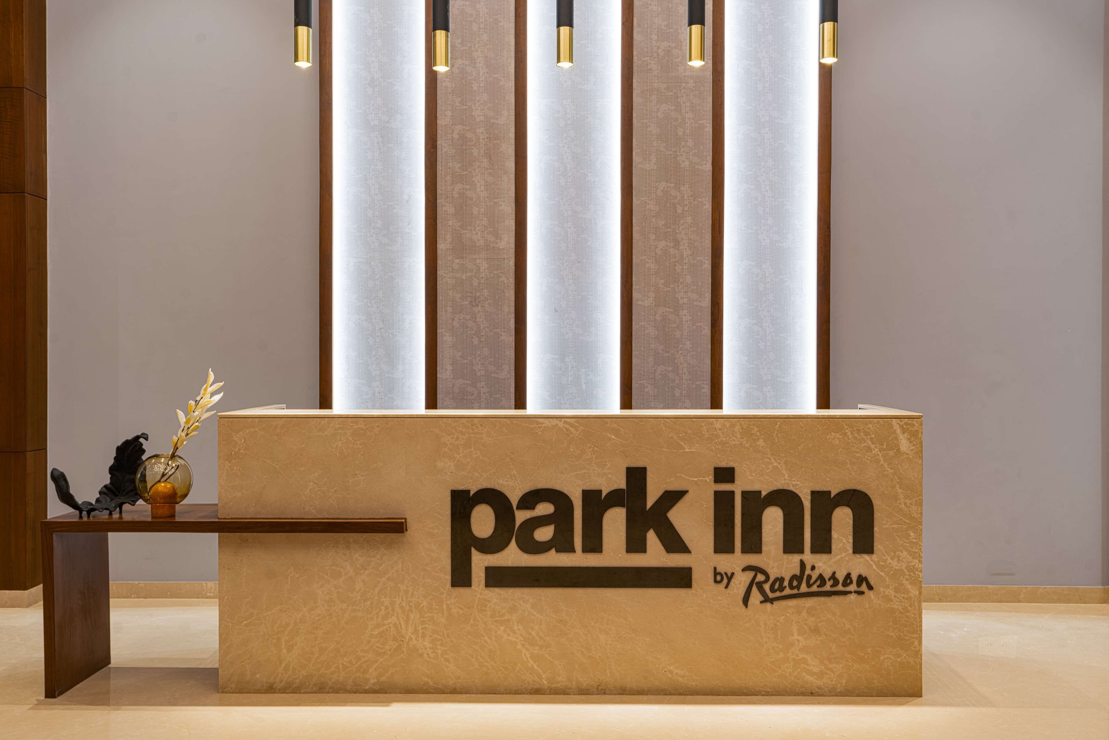 A reception desk with the text "park inn by Radisson" and a vase with flowers.