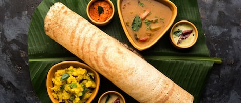 Una comida tradicional del sur de la India con dosa, sambar y chutney de coco, presentada sobre hoja de plátano.