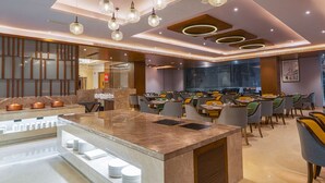 A modern restaurant with a central island, multiple dining tables, and a variety of chairs. - Park Inn By Radisson Ayodhya (Faizabad)