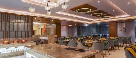 A modern restaurant with a central island, multiple dining tables, and a variety of chairs.