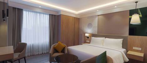 A hotel room with a bed, two armchairs, a small table, a desk, and a nightstand.