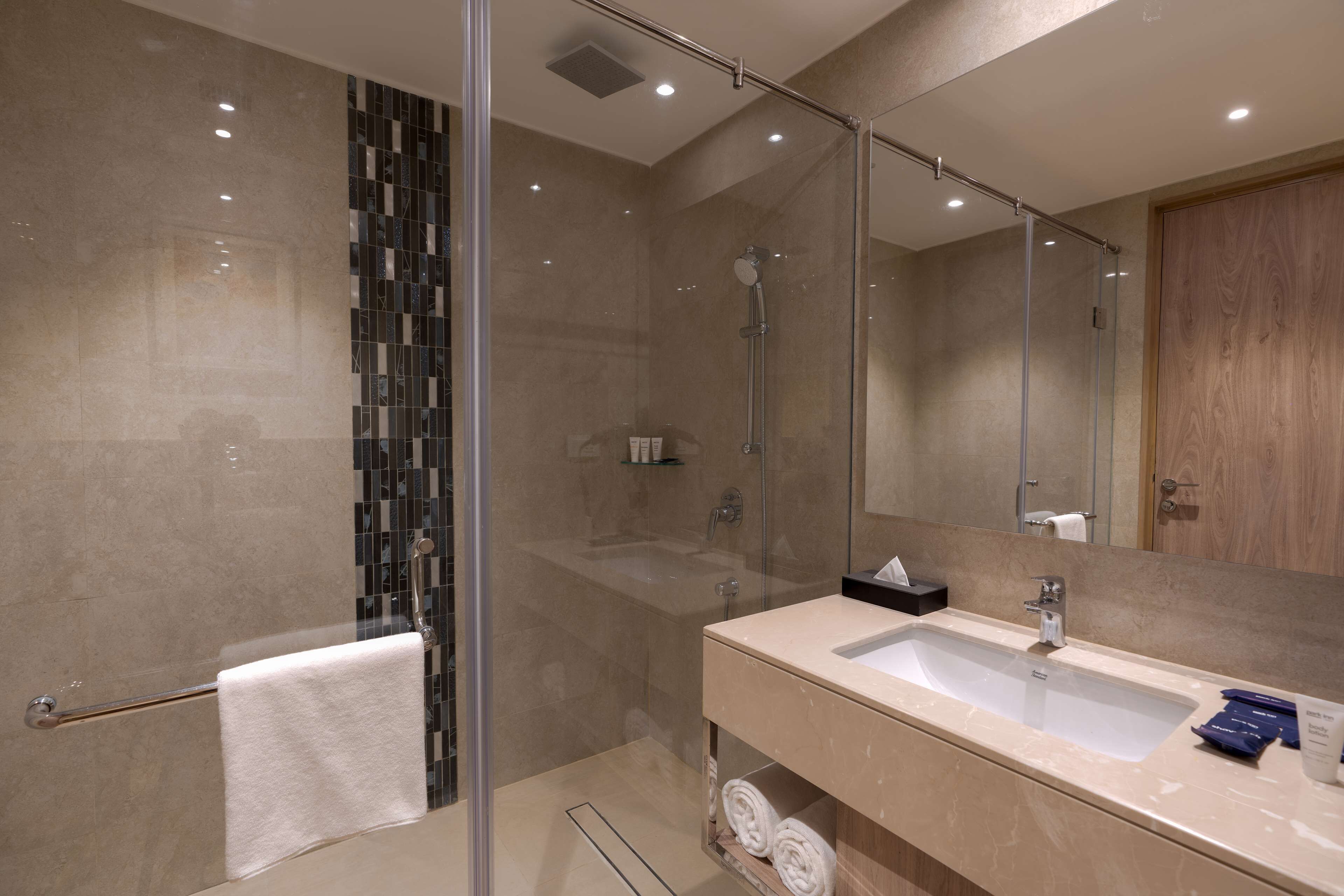 A modern bathroom with a glass-enclosed shower, a large sink, and a mirror.