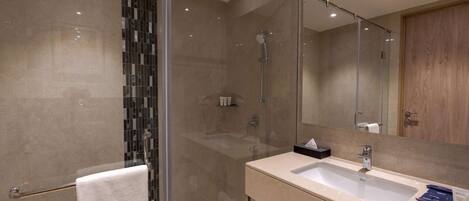 A modern bathroom with a glass-enclosed shower, a large sink, and a mirror.