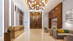A modern hotel lobby with a reception desk, seating area, and a decorative ceiling light fixture. - Park Inn By Radisson Ayodhya (Faizabad)