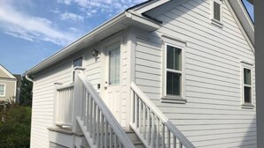 A two-story house with a white exterior, a front porch, and a staircase leading to the second floor. - Daniel Island Getaway (Charleston)
