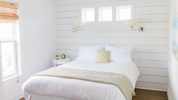 A bedroom with a large bed, a nightstand with a lamp, and a window with blinds. - Daniel Island Getaway (Charleston)