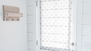 A white door with a patterned glass panel, a wooden sign with "WELCOME" above it, and a wall-mounted coat rack with hooks. - Daniel Island Getaway (Charleston)