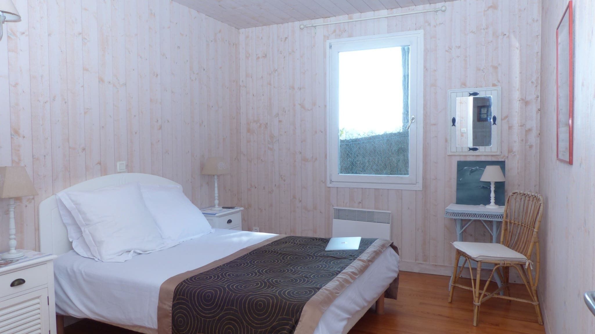 Une chambre à coucher avec un lit, des tables de chevet, une chaise, une fenêtre et un miroir.