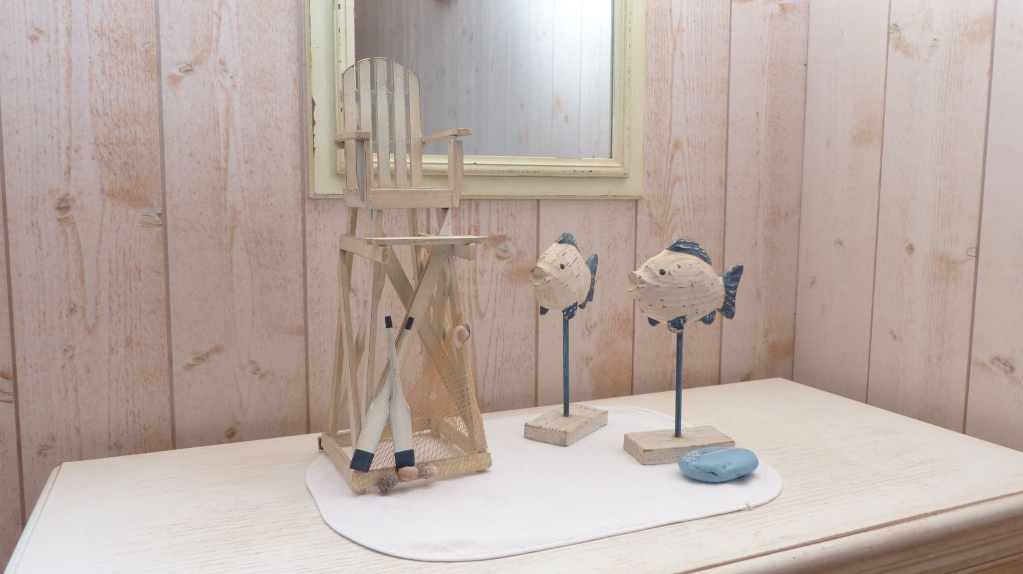 A wooden room with a small table, a mirror, and two fish-shaped decorations.