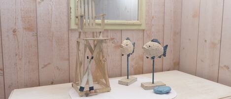 A wooden room with a small table, a mirror, and two fish-shaped decorations.