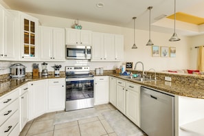 A kitchen with white cabinets, a microwave, stove, and dishwasher. - Steps to Beach: Oceanside Townhome w/ Heated Pool (South Padre Island)