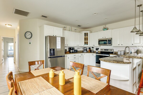 A modern kitchen with white cabinets, a stainless steel refrigerator, a microwave, and a granite countertop island. - Steps to Beach: Oceanside Townhome w/ Heated Pool (South Padre Island)