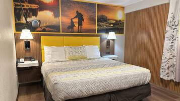 Habitación de hotel con una cama grande, dos mesitas de noche, un cabecero de madera y cuadros con escenas de golf y atardecer.