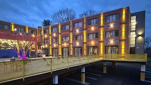 Un hôtel à plusieurs étages doté d’un espace extérieur couvert avec des sièges et d’un parking.