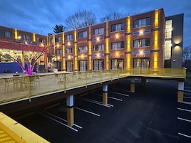 Un hotel de varios pisos con una zona de estar al aire libre techada y un estacionamiento.