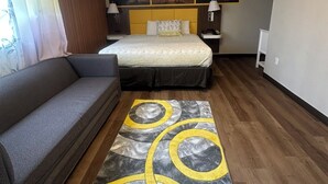 Une chambre d’hôtel avec un lit, un canapé, un tapis et des œuvres d’art accrochées au mur.