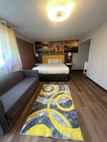 Una habitación de hotel con cama, sofá, alfombra y obras de arte en la pared.