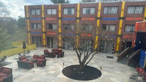 A multi-story building with a checkered tile floor, outdoor seating area, and a tree in the center.