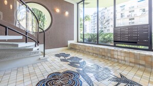 Un interior moderno con una escalera, un ventanal con vistas a edificios y un suelo de baldosas con un estampado floral.