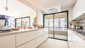 Una cocina moderna con armarios blancos, horno empotrado y un amplio ventanal con vistas a la ciudad.
