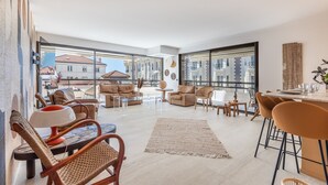 Un salón amplio con un gran ventanal, muebles de mimbre y una moderna zona de comedor.