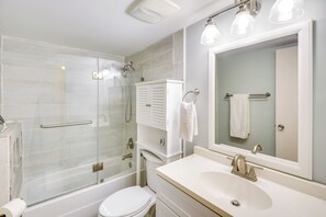 A modern bathroom with a glass-enclosed shower, a white toilet, a sink with a mirror, and a towel rack. - New Smyrna Beach Condo w/ Ocean-View Balcony! (New Smyrna Beach)