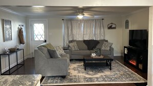 Una sala de estar con sofá, sillón, mesa de centro y chimenea.