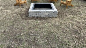 Un hogar de piedra rodeado por cuatro sillas de madera tipo Adirondack en un jardín cubierto de césped.