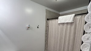 Un baño con cortina de ducha, inodoro, lavamanos y un perchero con toallas.